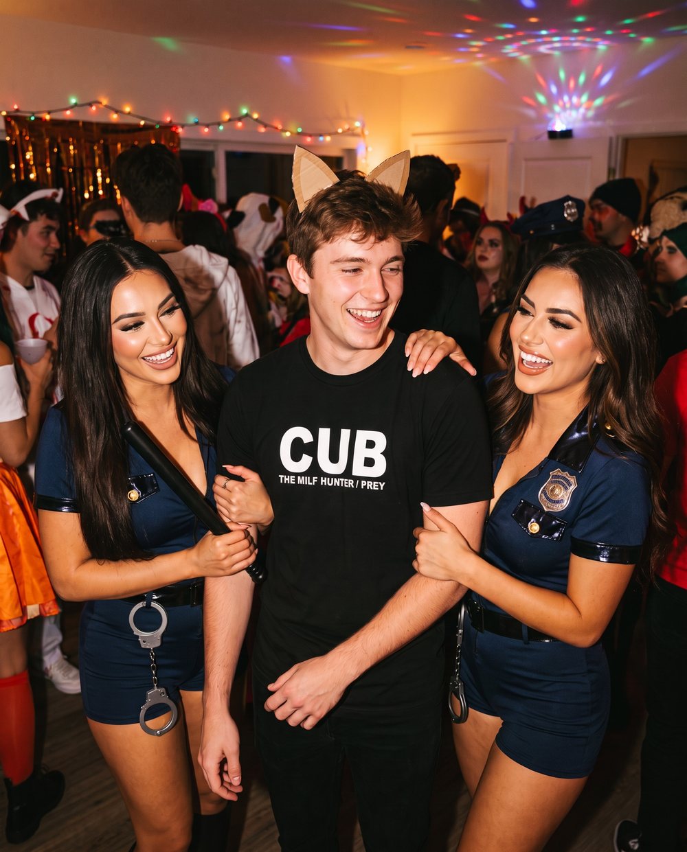 Two women dressed as cops arresting a guy in the CUB Milf Hunter tee